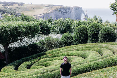 Portrait of a man in a botanical garden in geometric bushes.