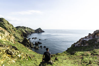 Rear view of man walking on mountain against clear sky - eo gio -wind strait