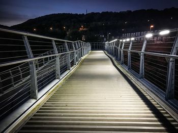 Illuminated footbridge against sky at night