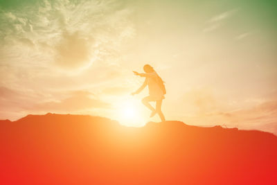 Silhouette man standing on mountain against sky during sunset