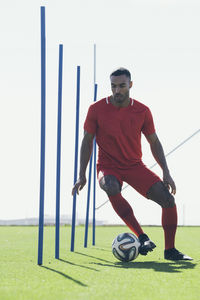 African american male soccer player practicing on grass pitch