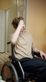 Young man sitting on wheelchair at home