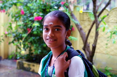 Portrait of smiling young woman standing against trees