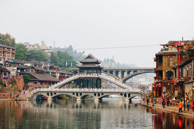 Bridge over river in city against clear sky