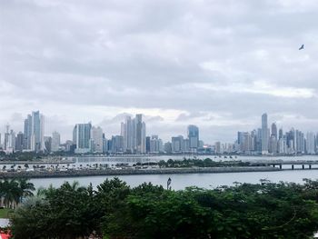 Sea by buildings against sky in city