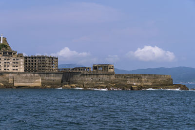 Buildings by sea against blue sky