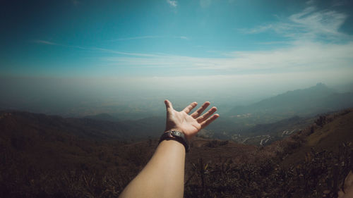 Cropped hand against mountains