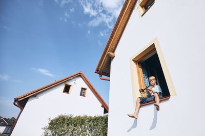 Low angle view of woman by house against sky