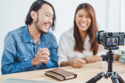 Smiling young woman photographing while sitting on table