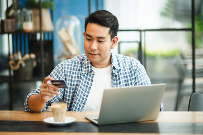 Man using phone while sitting on table at cafe