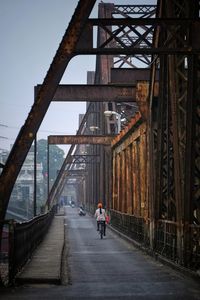 Rear view of man walking on bridge