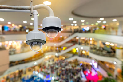 Closeup cctv security camera on blurred inside shopping mall background.