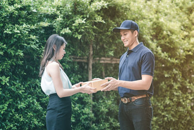 Side view of young couple standing against trees