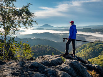 Photographer on cliff carry tripod. blogger hold tripod with camera. man at sunrise at open view