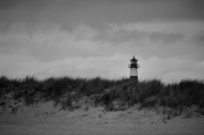 Lighthouse by sea against sky