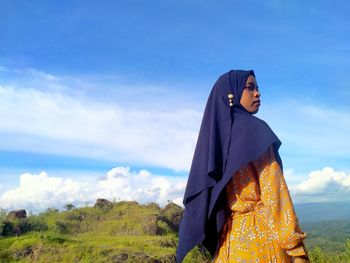 Woman standing on cross against sky