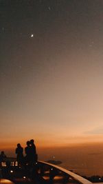 Silhouette city by sea against sky at night