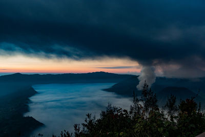 Active volcano at mt bromo against cloudy sky during sunset