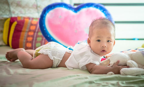 Portrait of newborn baby girl lying on bed at home