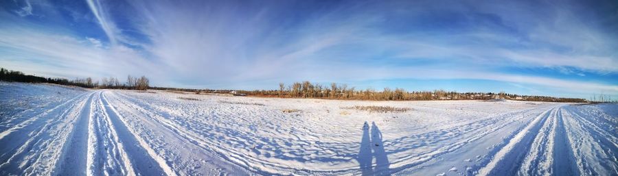 Panoramic view of snow covered field against sky