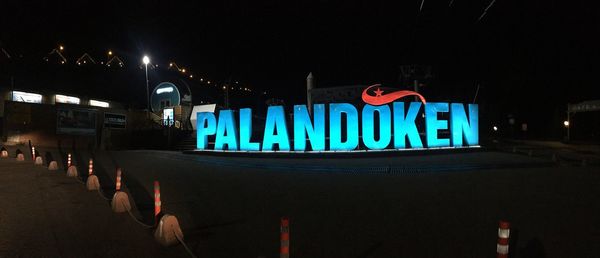 Illuminated text written on street in city at night