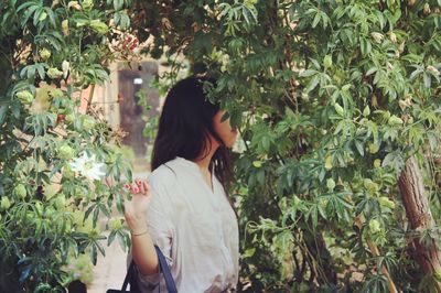 Woman looking up while sitting on tree trunk