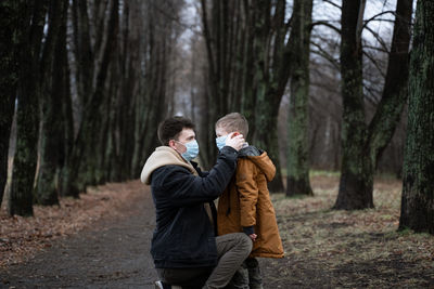 Father wearing mask to son in forest