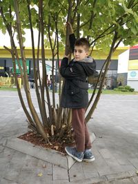 Full length portrait of girl standing by tree