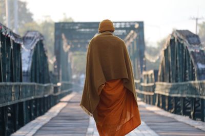 Rear view of monk walking on footbridge