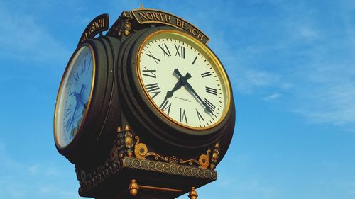 Low angle view of clock against blue sky