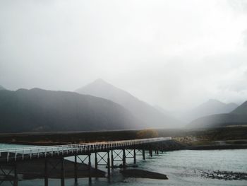 Scenic view of river by mountains against sky