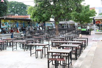 Empty chairs and tables at sidewalk cafe by buildings in city