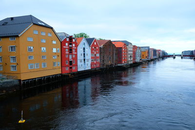 Buildings by river against sky in city