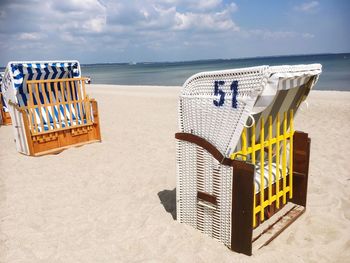 Hooded beach chairs on sand during sunny day