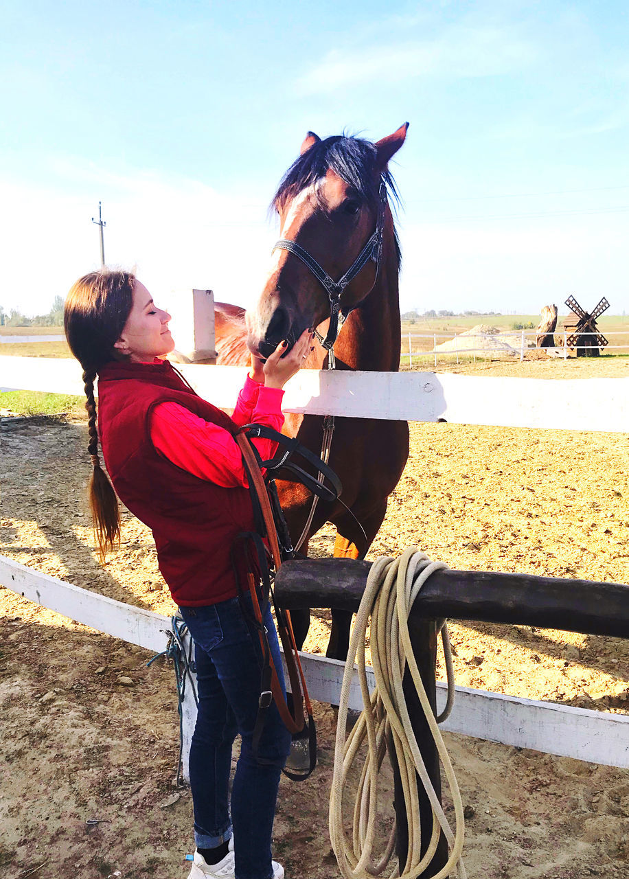 horse, nature, adult, sky, sunlight, land, two people, women, animal, day, domestic animals, leisure activity, beach, men, animal themes, full length, water, female, togetherness, lifestyles, mammal, outdoors, activity, pet, sea, sand, young adult, animal wildlife, transportation, standing, casual clothing, child, livestock, clothing, sports