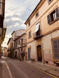 Empty road amidst buildings in city against sky