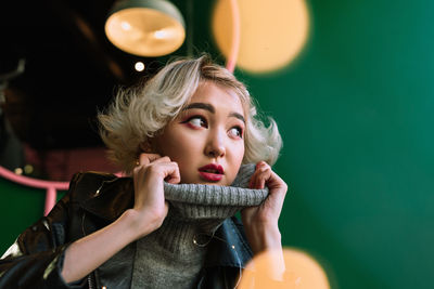 Young woman looking away against wall