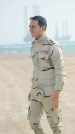 Smiling army soldier looking away while standing on land