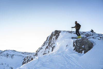 Man standing on snowcapped mountain against clear sky