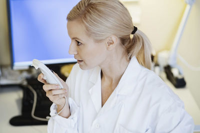 Female doctor using dictation device in office