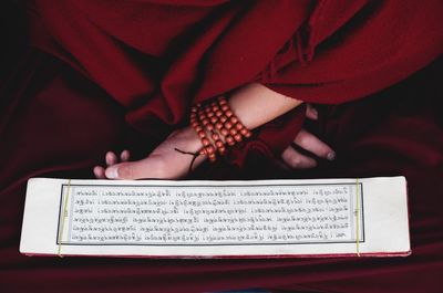 Midsection of monk reading text on paper