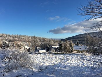 Snow covered landscape and buildings against sky