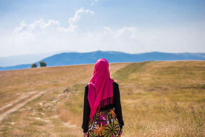 Rear view of woman walking on field