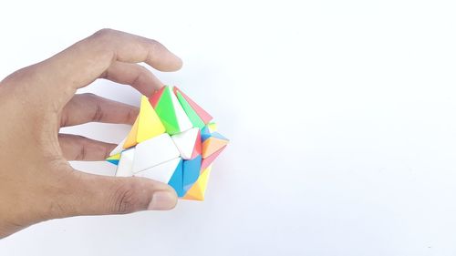 Close-up of hand holding multi colored pencils over white background