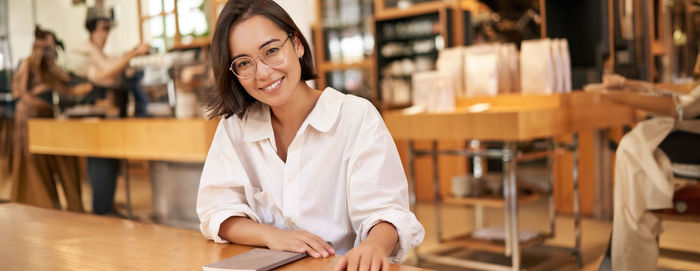 Portrait of young woman using mobile phone in cafe