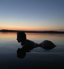Man on shore against sky during sunset