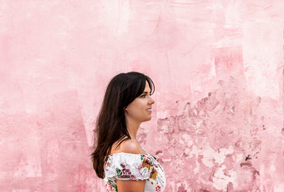 Portrait of a beautiful young woman against pink wall.
