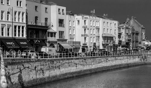 Buildings by river against sky in city