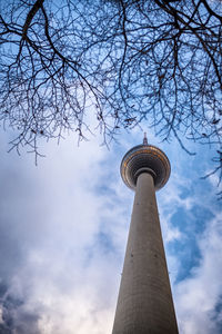 Low angle view of communications tower against cloudy sky