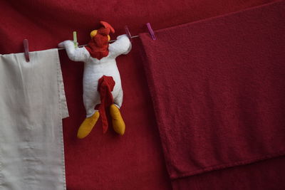 Stuffed toy hanging on clothesline against red textile